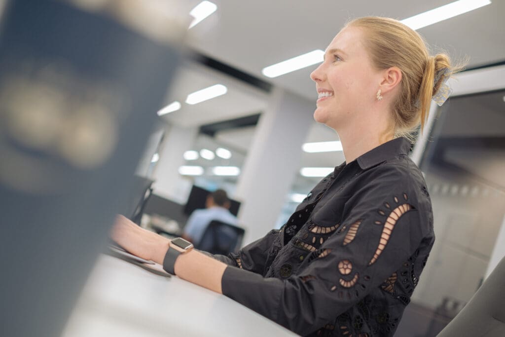 women with blond hair working at desk in black shirt with design cutouts