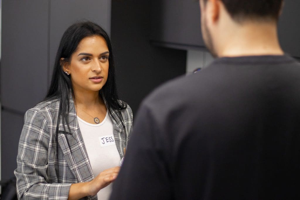 women in grey checkered jacket talking to man in black shirt