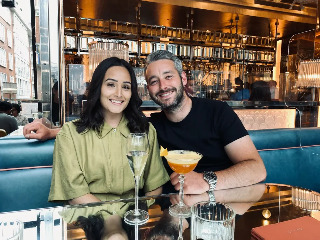 man and women sat a table in restaurant with cocktails