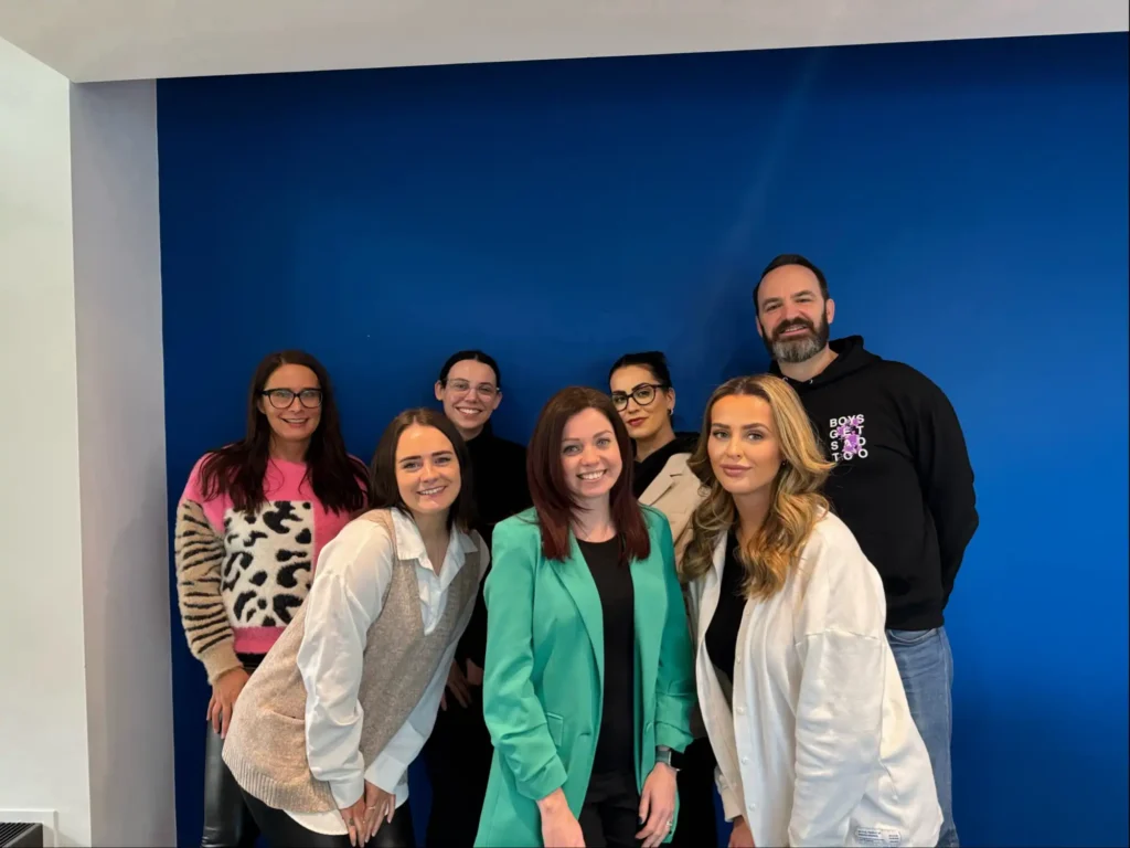 ta team posing in front on blue wall