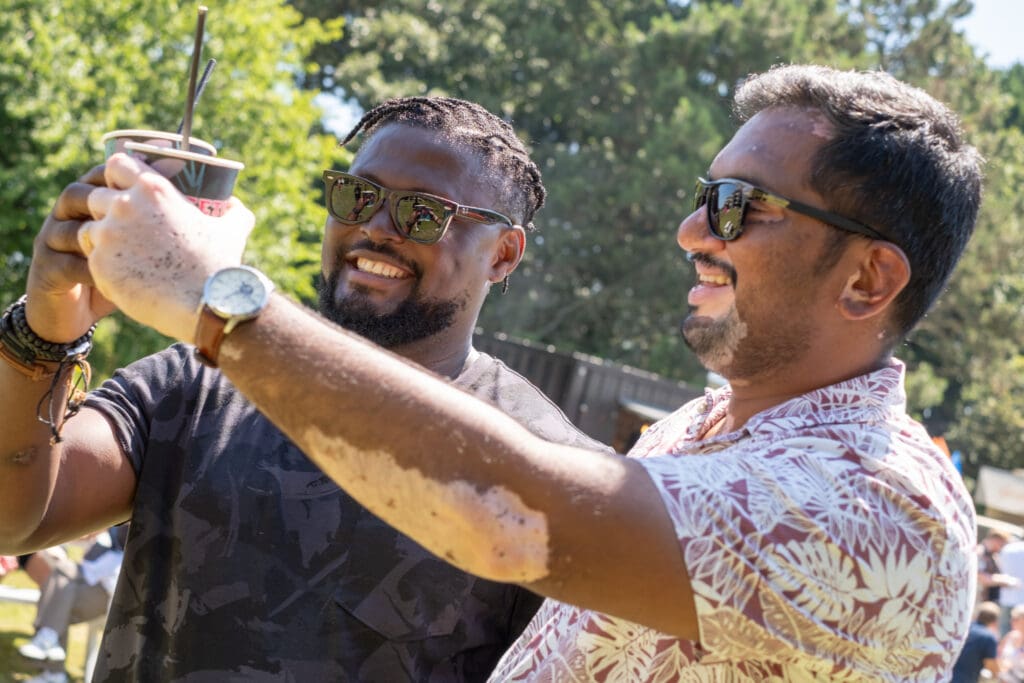 2 guys toasting their glasses at an outdoor event